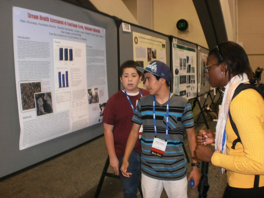 Three students looking at a science poster